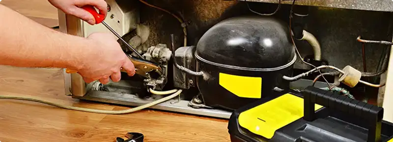 Refrigerator repair technician fixing the compressor and wiring in Lone Tree, CO