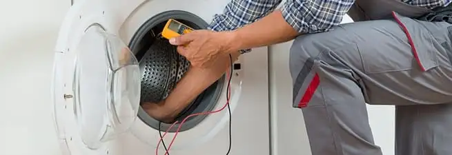 Dryer repair technician inspecting and repairing a clothes dryer in Aurora, CO