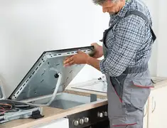 Appliance repair technician installing a built-in cooktop in Aurora, CO