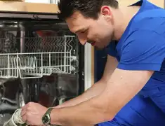 Dishwasher repair technician inspecting and servicing an open dishwasher in Aurora, CO