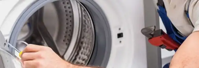 Appliance technician repairing a clothes dryer drum and internal parts in Aurora, CO