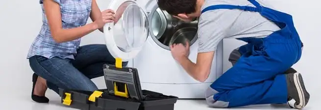 Washer repair technician inspecting a front-load washing machine with tools in Aurora, CO