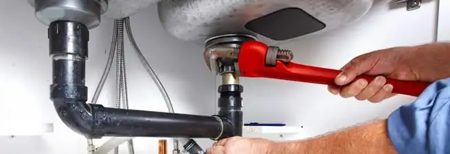 Garbage disposal repair technician tightening the sink drain and disposal connection in Aurora, CO