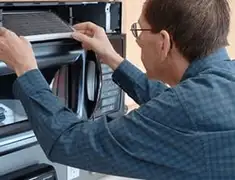 Appliance repair technician replacing a microwave vent filter in Aurora, CO