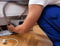 Appliance repair technician fixing refrigerator water line and connections in Aurora, CO