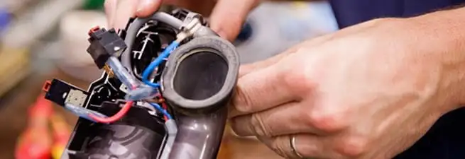Vacuum repair technician reconnecting wiring and components in Aurora, CO