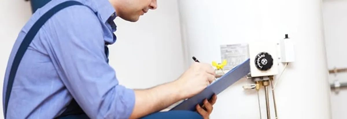 Water heater repair technician inspecting the unit and recording service notes in Aurora, CO