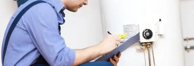 Water heater repair technician inspecting the unit and recording service notes in Aurora, CO