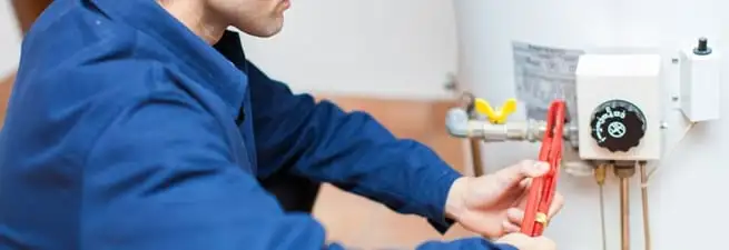 Water heater repair technician adjusting the temperature control and gas valve in Aurora, CO